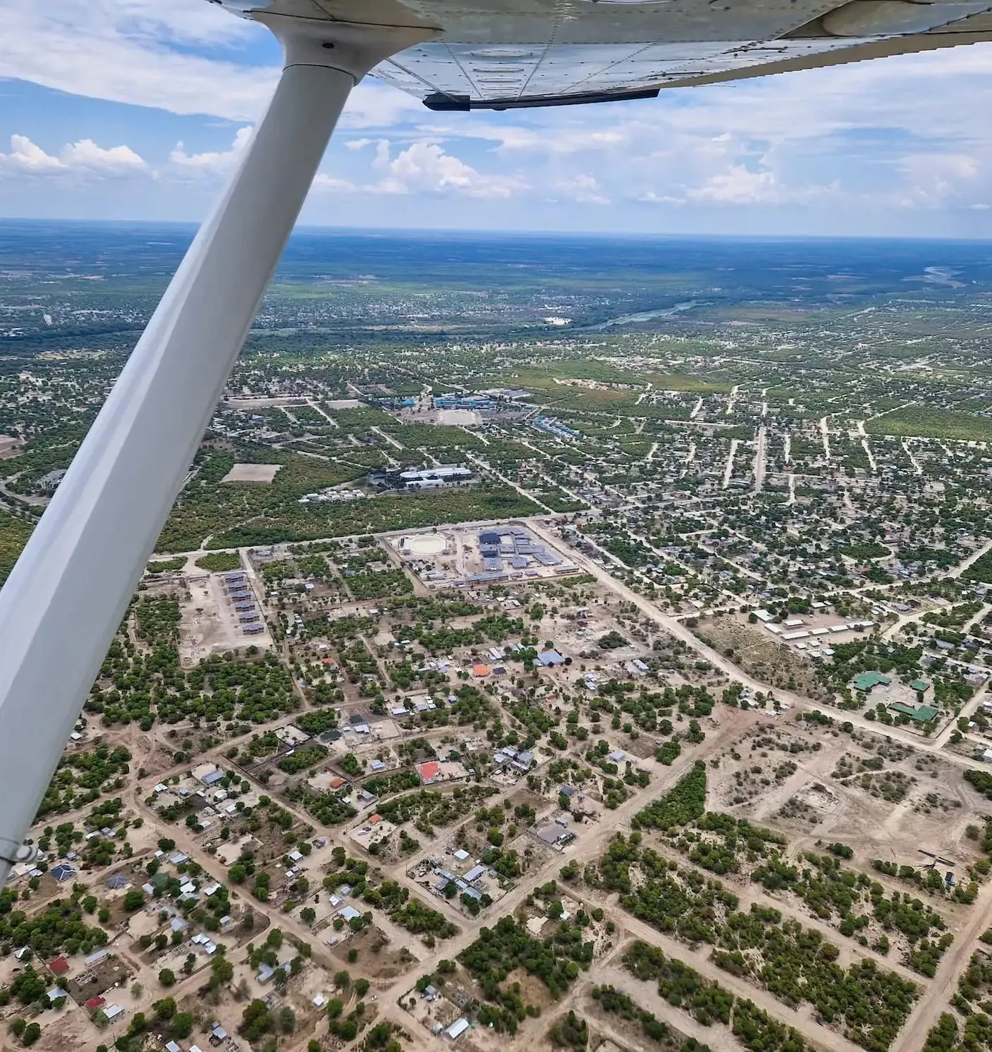 Blick aus dem Kleinflugzeug auf Maun, weit verstreute Häuser zwischen Sandpisten