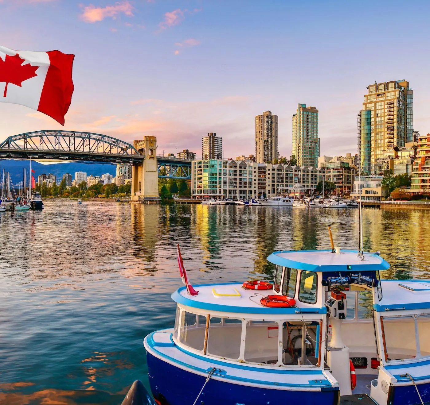 Die Skyline von Vancouver im Abendlicht, davor eine kleine Fähre am Steg