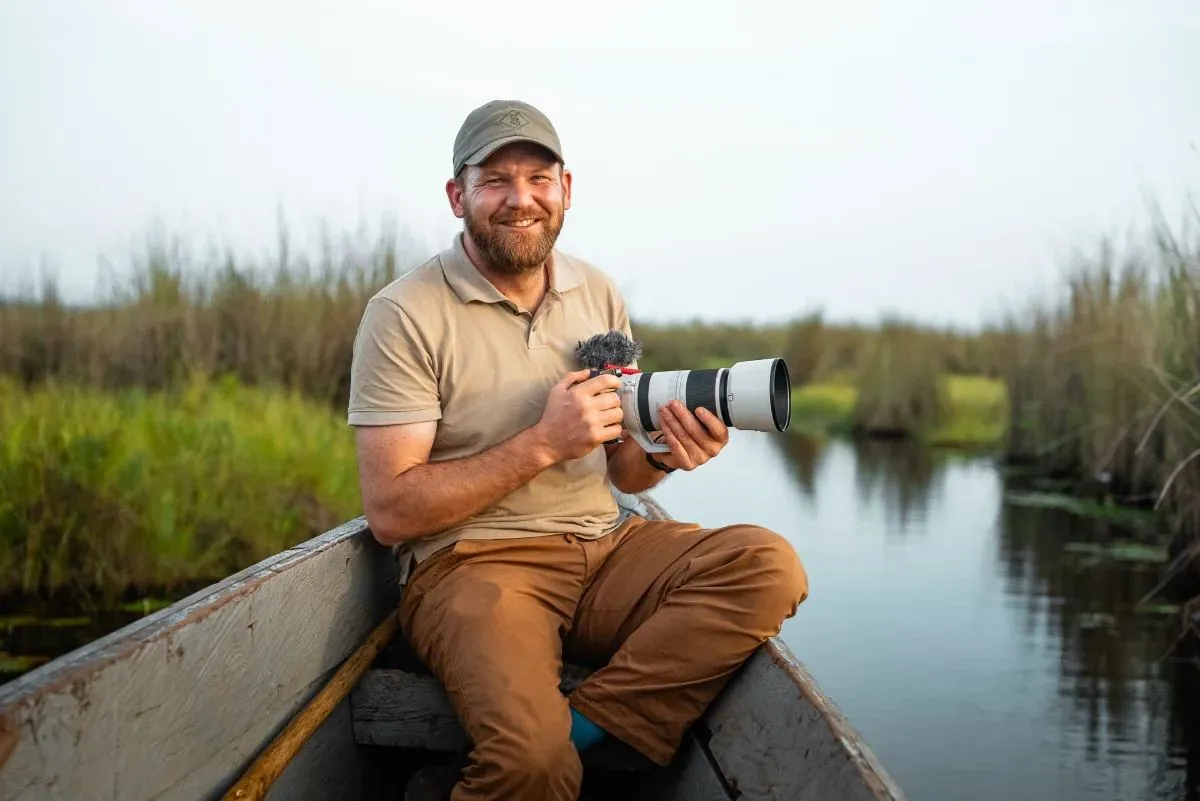 Fotograf mit Teleobjektiv im Boot auf einem schmalen Sumpfkanal