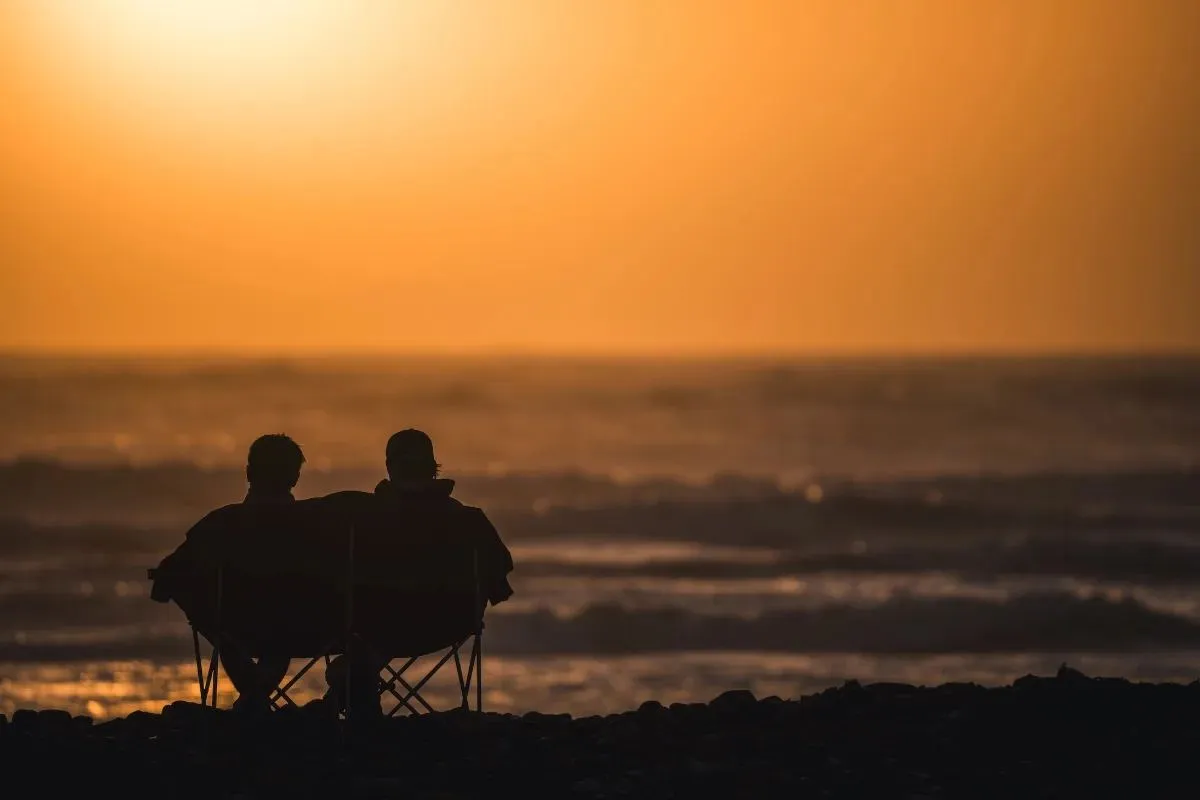 Zwei Campingstühle am Meer im Gegenlicht der Abendsonne