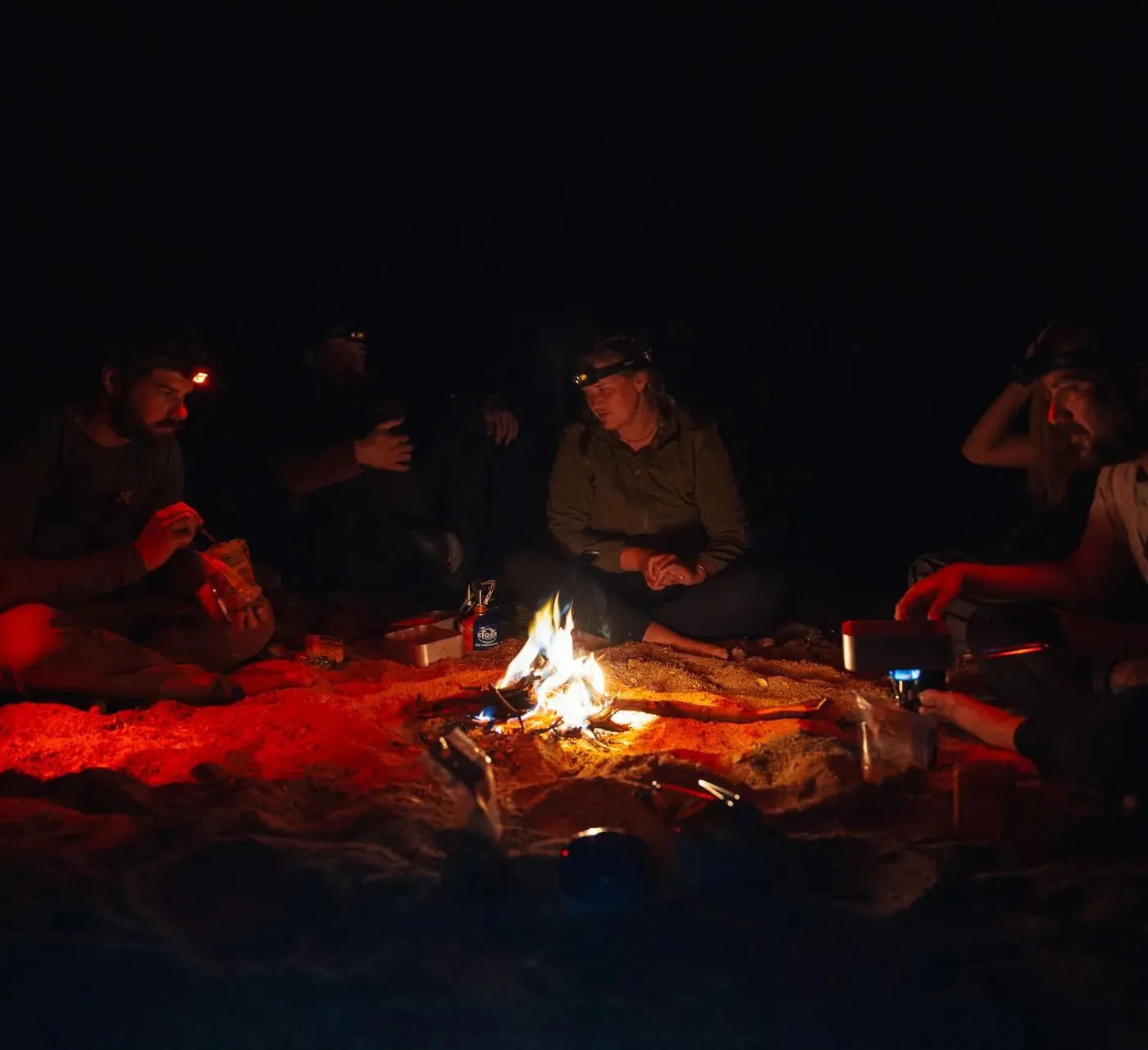 Nachts am Lagerfeuer, Stirnlampen im Kreis um die Flammen