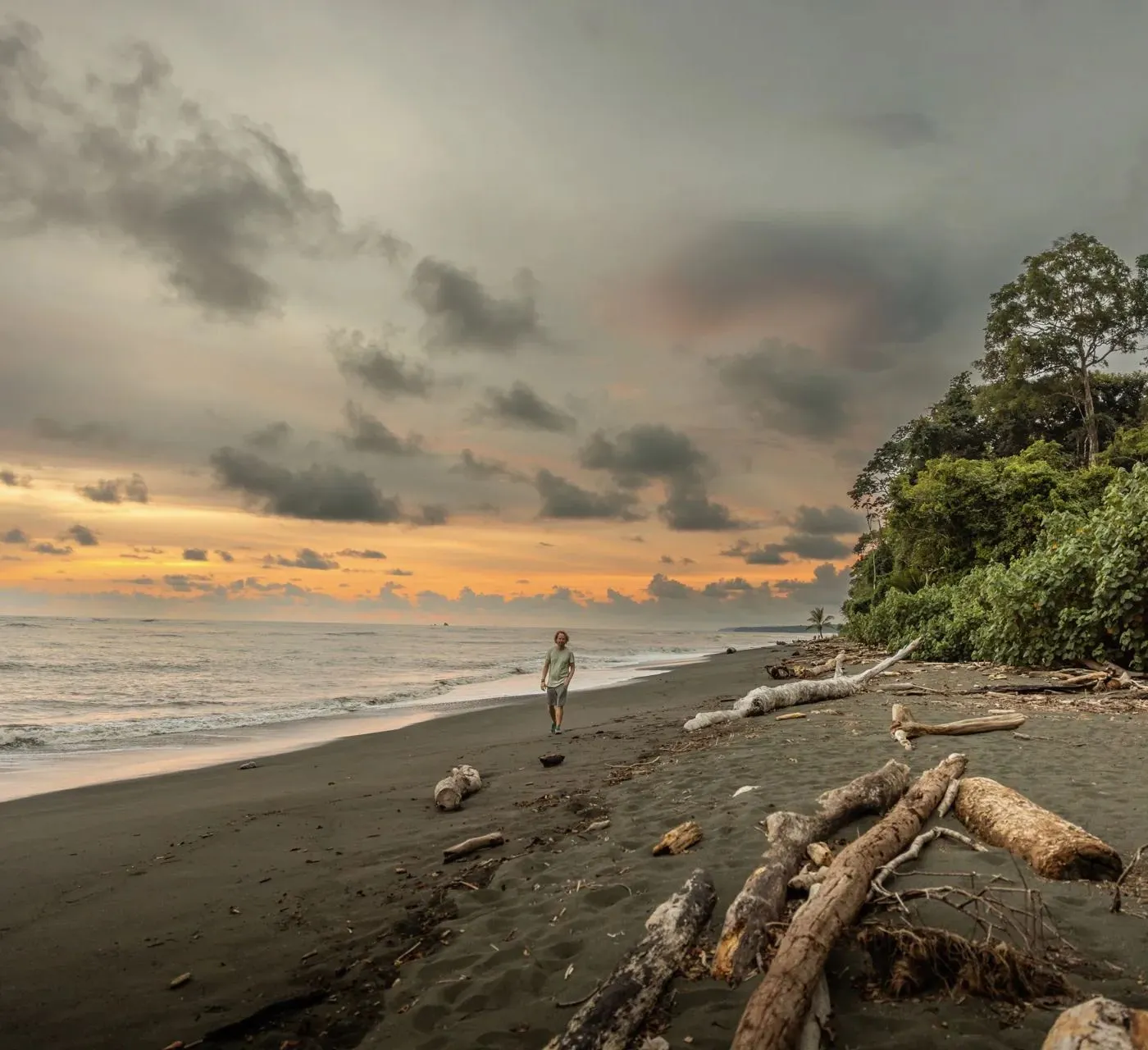 Einzelne Person am weiten Strand unter Abendwolken