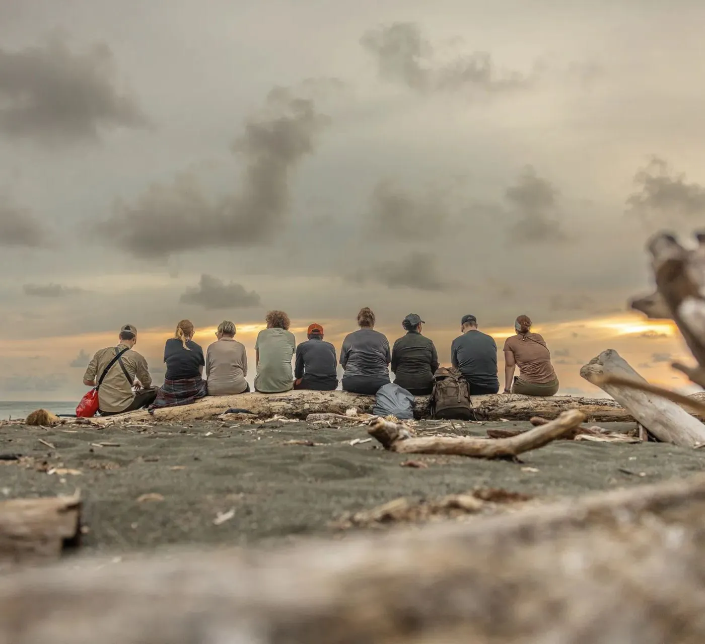 Die Gruppe sitzt am Strand und schaut in den Sonnenuntergang